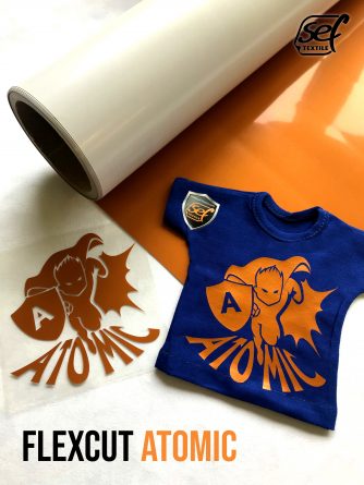 Película de transferencia y corte para aplicación textil en color naranja brillante, aplicada a una camiseta azul para la demostración del producto.